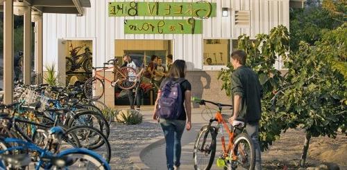 two students walk towards the green bike program building.